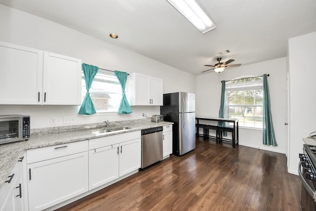 kitchen with appliances with stainless steel finishes, white cabinetry, a sink, and light stone counters