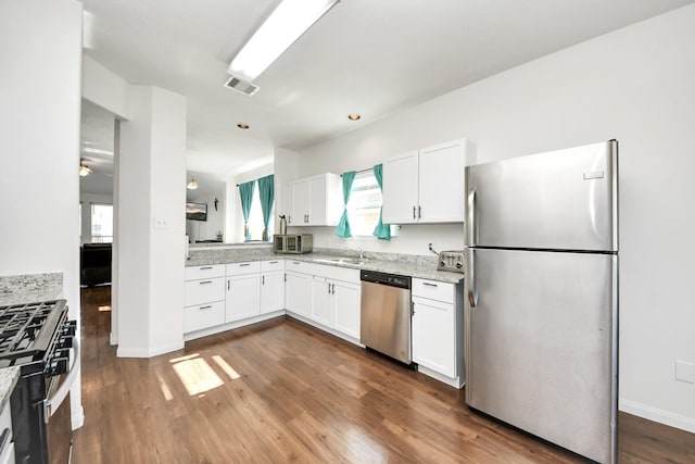 kitchen featuring dark wood-style floors, white cabinetry, appliances with stainless steel finishes, and a wealth of natural light