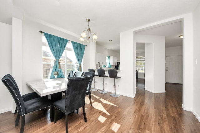 dining room featuring a chandelier, wood finished floors, and baseboards