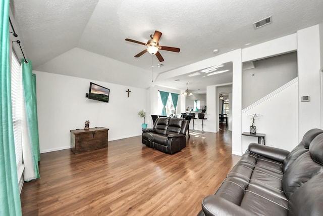 living room with visible vents, ceiling fan, wood finished floors, vaulted ceiling, and a textured ceiling