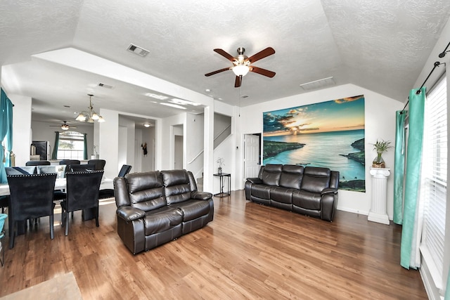 living area featuring lofted ceiling, visible vents, a textured ceiling, and wood finished floors