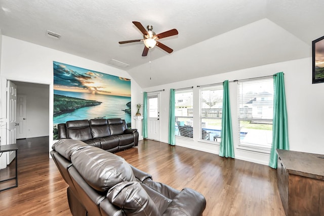 living room with dark wood-style floors, visible vents, vaulted ceiling, and a ceiling fan