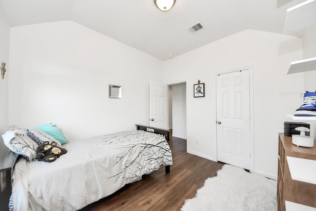 bedroom with dark wood-style floors, lofted ceiling, visible vents, and baseboards