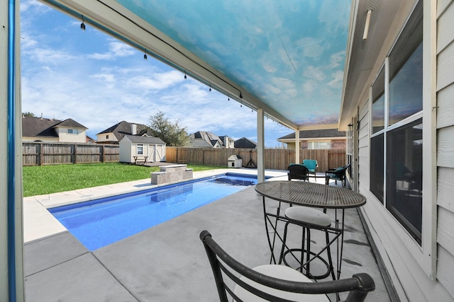 view of swimming pool featuring a storage shed, a fenced in pool, a patio, a fenced backyard, and an outbuilding