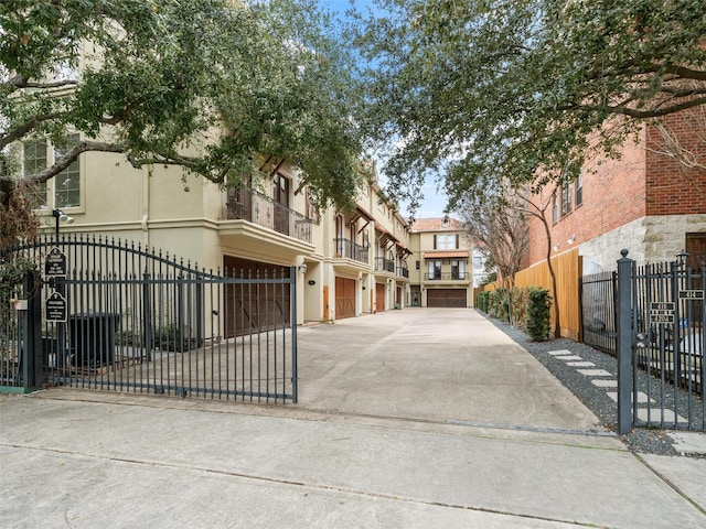 view of front facade featuring stucco siding, an attached garage, fence, a residential view, and driveway