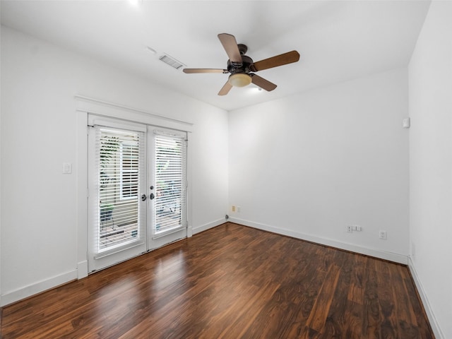 empty room featuring dark wood-style floors, baseboards, visible vents, and a ceiling fan