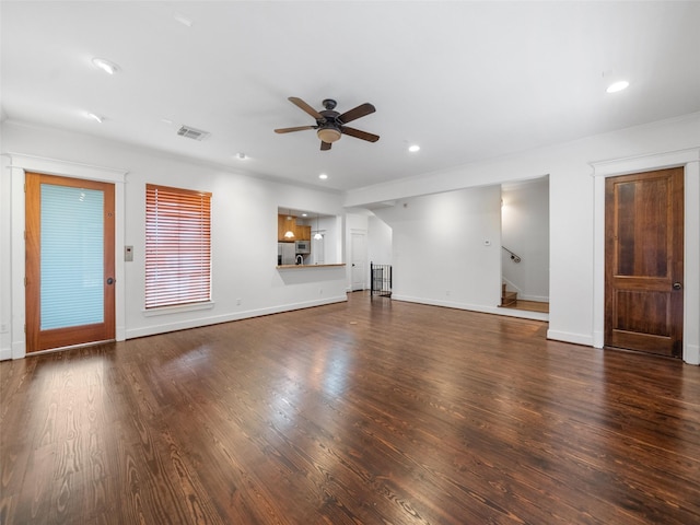 unfurnished living room with dark wood-type flooring, visible vents, ceiling fan, and stairway