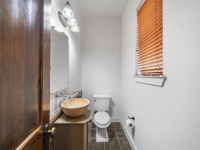 bathroom featuring toilet, vanity, and baseboards