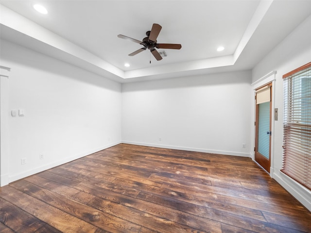 spare room featuring ceiling fan, recessed lighting, dark wood-style flooring, baseboards, and a tray ceiling