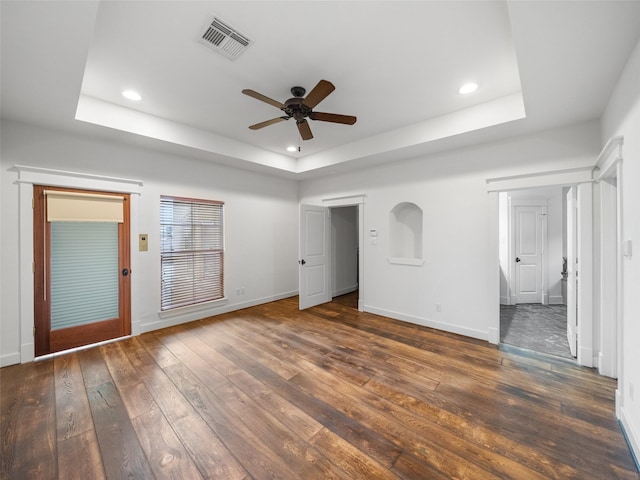 unfurnished bedroom with dark wood-type flooring, a raised ceiling, visible vents, and baseboards