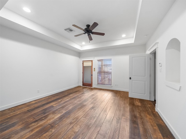 spare room featuring recessed lighting, a raised ceiling, visible vents, dark wood-type flooring, and baseboards