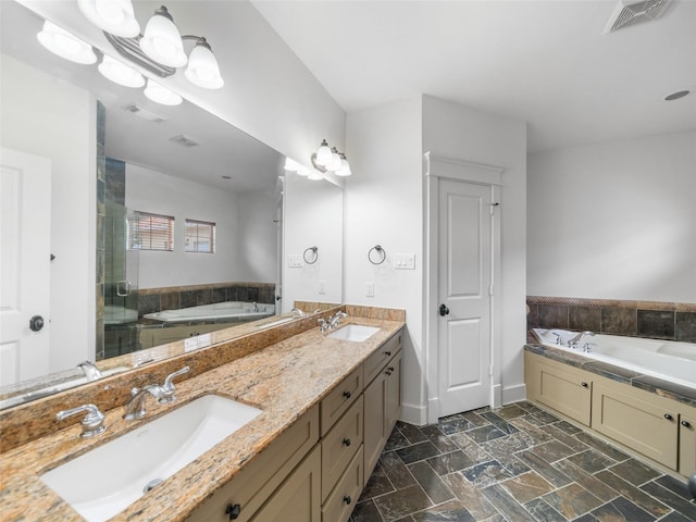 full bathroom with a bath, double vanity, a sink, and visible vents