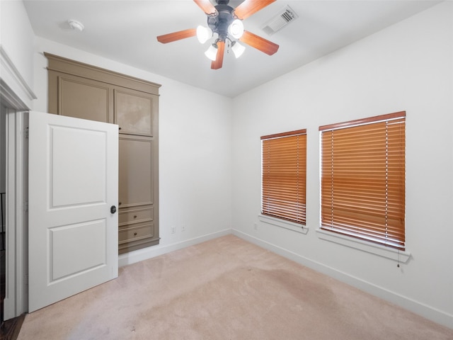 unfurnished room with light carpet, baseboards, visible vents, and a ceiling fan