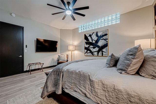 bedroom with light wood finished floors, a ceiling fan, and baseboards