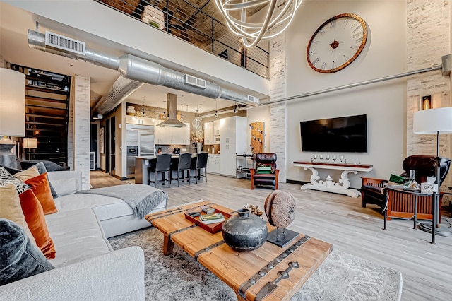 living room with wood finished floors, a towering ceiling, and visible vents