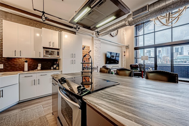 505 Bastrop St Unit 508, Houston, TX 77003 - kitchen featuring stainless steel appliances, backsplash, white cabinets, light wood-type flooring, and light countertops