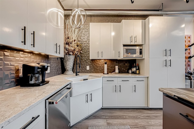 kitchen with hanging light fixtures, appliances with stainless steel finishes, and white cabinets