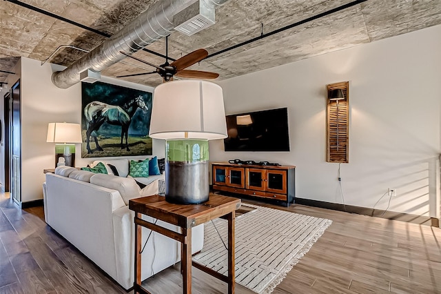 living room with a ceiling fan, visible vents, baseboards, and wood finished floors