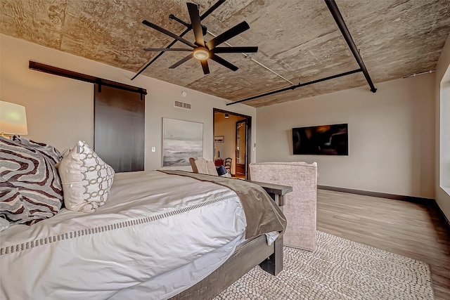 505 Bastrop St Unit 508, Houston, TX 77003 - bedroom with wood finished floors, a barn door, baseboards, and ceiling fan