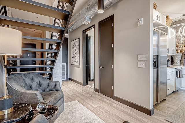 living area featuring visible vents, light wood-style flooring, and baseboards