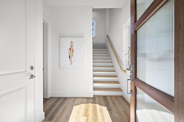 entrance foyer with light wood-type flooring, stairs, and baseboards