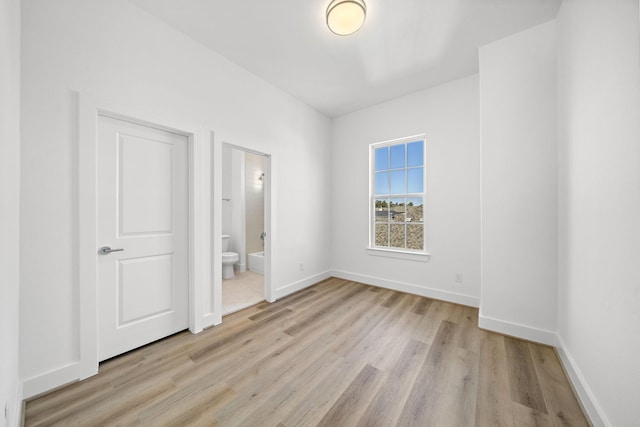 unfurnished bedroom with light wood-type flooring, ensuite bath, and baseboards