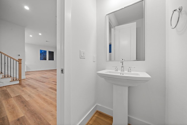 bathroom with a sink, recessed lighting, wood finished floors, and baseboards