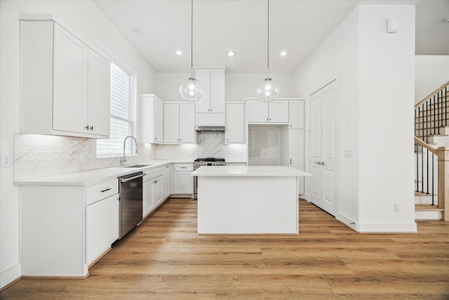 kitchen with a center island, pendant lighting, stainless steel appliances, light countertops, and white cabinetry