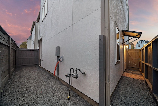 view of side of home with fence, a gate, and stucco siding