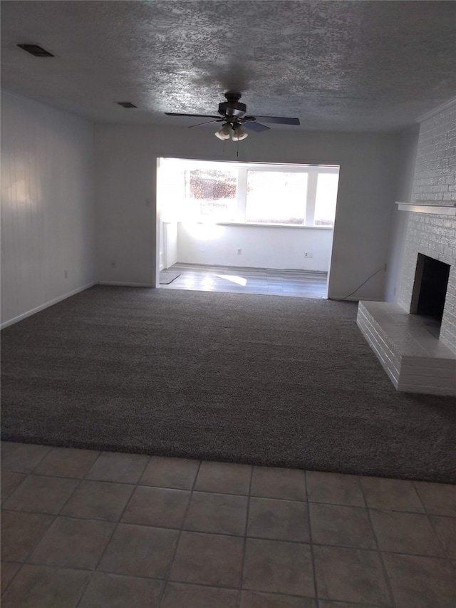 unfurnished living room featuring a textured ceiling, carpet floors, a fireplace, and tile patterned floors