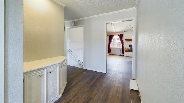 hallway featuring crown molding, a textured wall, dark wood-type flooring, a textured ceiling, and an upstairs landing