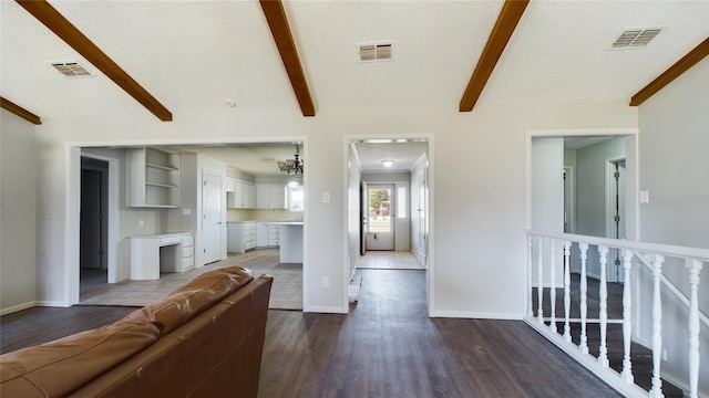 living room with visible vents, beamed ceiling, a textured ceiling, and wood finished floors