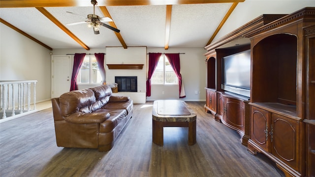 living area with baseboards, lofted ceiling with beams, dark wood-type flooring, a textured ceiling, and a brick fireplace