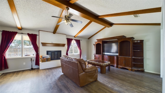 living area with a wealth of natural light, a brick fireplace, vaulted ceiling with beams, and a textured ceiling