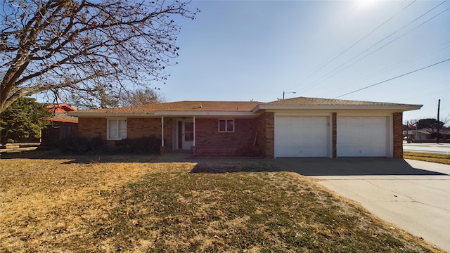 single story home with driveway, brick siding, an attached garage, and a front yard