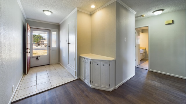 doorway featuring light wood-type flooring, crown molding, a textured ceiling, and baseboards