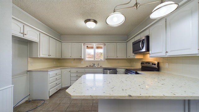 kitchen with white cabinets, stainless steel appliances, light countertops, and decorative light fixtures