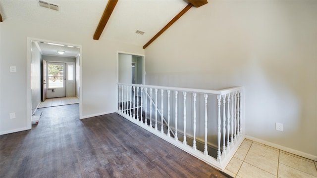 hallway with visible vents, vaulted ceiling with beams, and baseboards