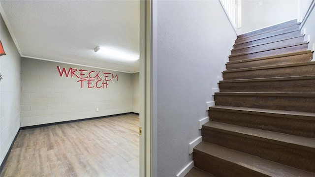 stairway with a textured ceiling and wood finished floors