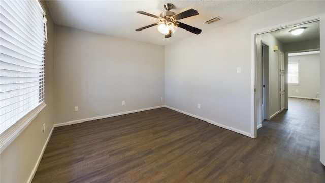 empty room featuring dark wood-style floors, baseboards, visible vents, and ceiling fan