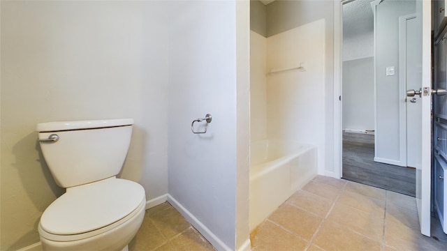 bathroom with a washtub, baseboards, toilet, and tile patterned floors