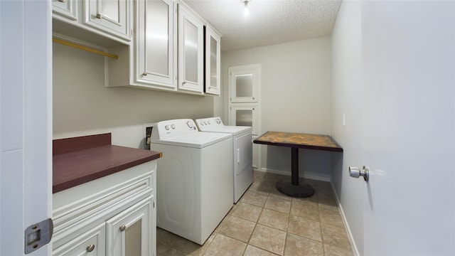 washroom featuring cabinet space, light tile patterned floors, baseboards, a textured ceiling, and washer and dryer