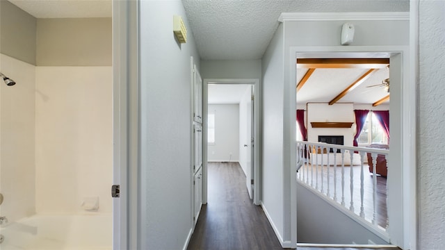 hallway with dark wood-type flooring, a textured ceiling, and baseboards