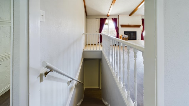 staircase featuring a textured wall and a fireplace