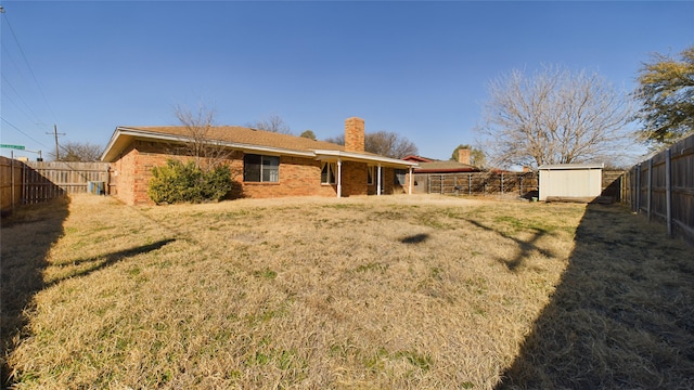 rear view of property featuring a storage shed, a fenced backyard, brick siding, and an outdoor structure