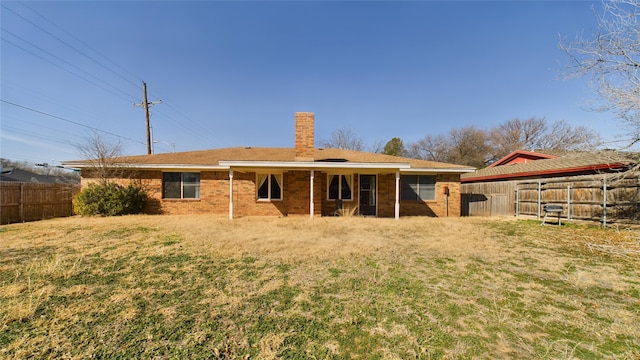 rear view of house with brick siding, a chimney, and a fenced backyard