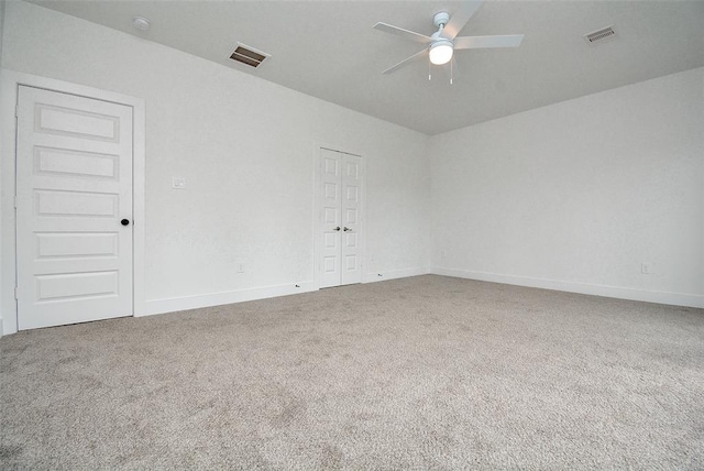 carpeted spare room with baseboards, visible vents, and a ceiling fan