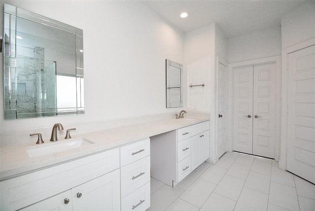 full bathroom with double vanity, a shower stall, a closet, and a sink