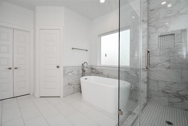 bathroom featuring a closet, tile walls, a freestanding tub, and a shower stall