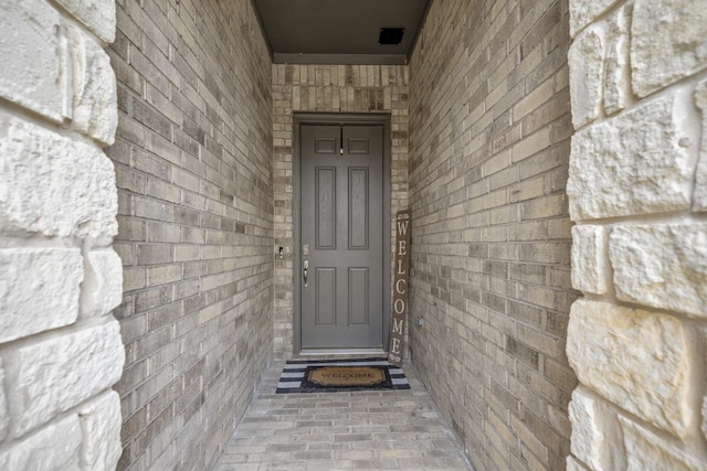 doorway to property featuring brick siding